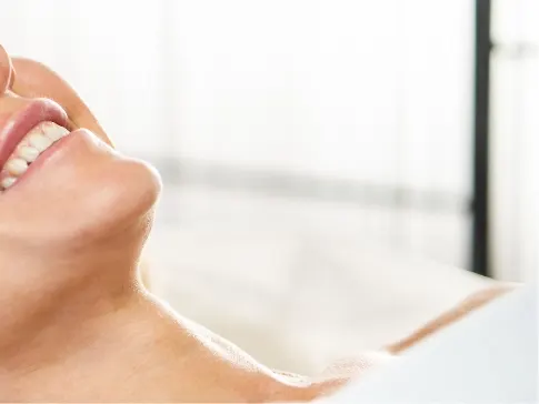 Stock photograph of a model: a smiling woman wearing a white headband lies back with her eyes closed