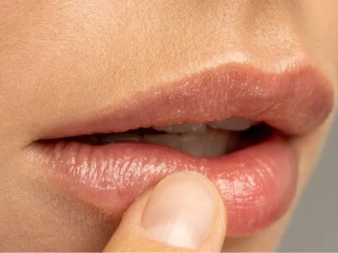 Stock photograph of a model: a close view of a woman's lips as she touches her lower lip with a fingertip