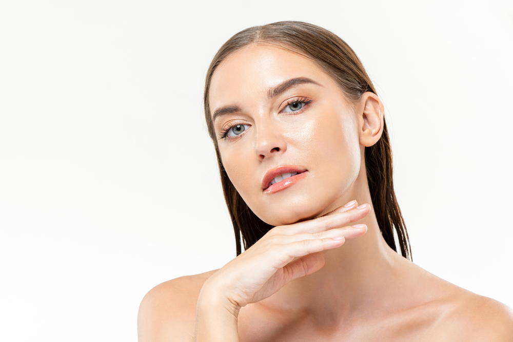 Stock photograph of a model: a woman with smooth, even skin rests her hand under her chin