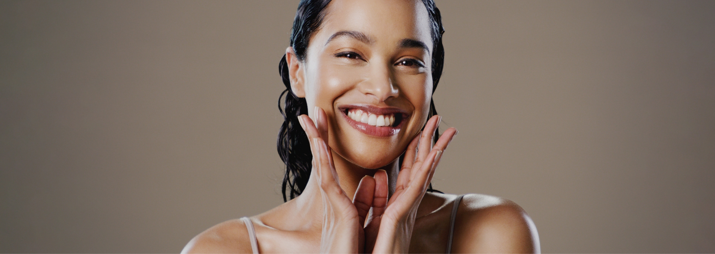 Stock photograph of a model: a smiling woman touches her cheeks with both hands