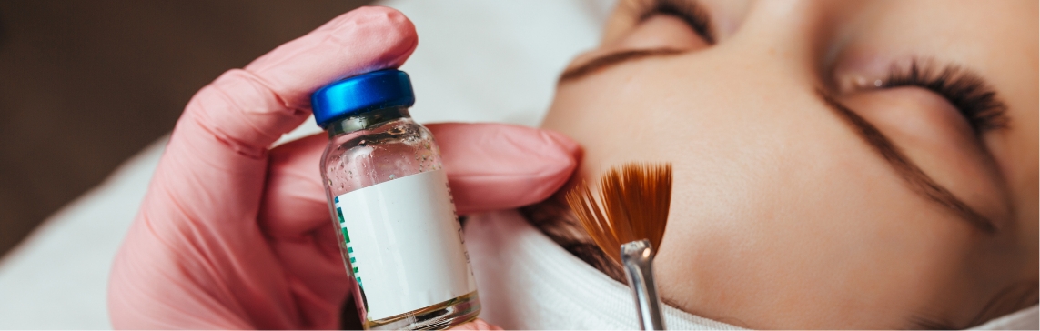 Stock photograph of a model: a pink-gloved hand holds a small vial while a fan brush is poised beside a woman's closed eye