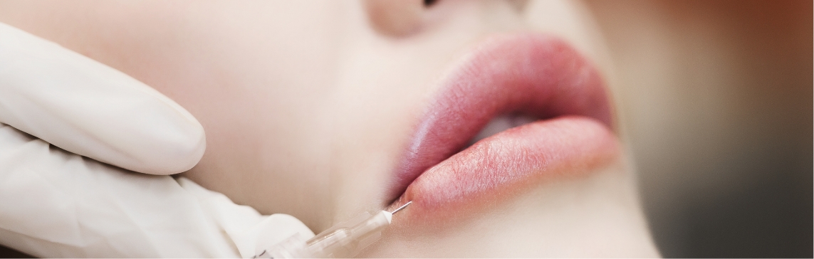 Stock photograph of a model: a gloved hand holds a fine needle at a woman's lower lip
