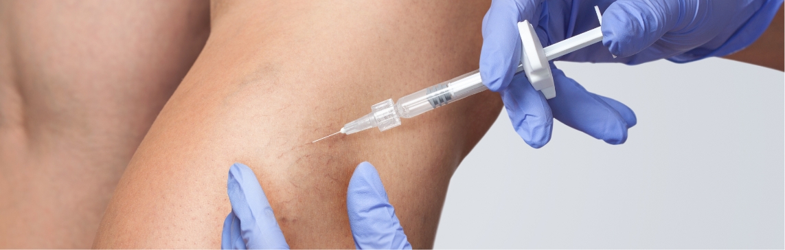 Stock photograph: blue-gloved hands inject a syringe into a leg that shows small visible veins