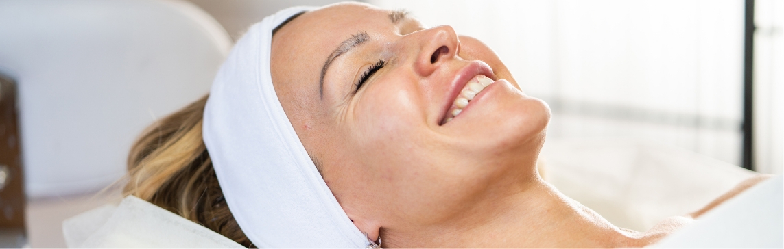 Stock photograph of a model: a smiling woman wearing a white headband lies back with her eyes closed