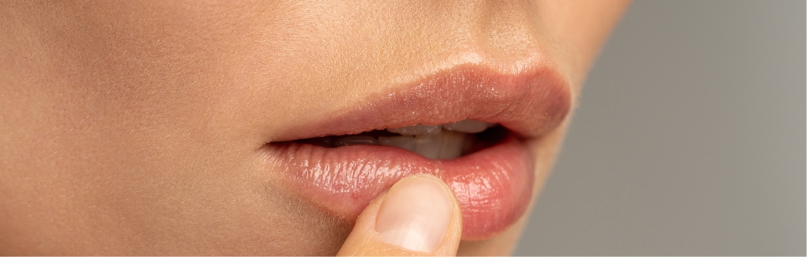Stock photograph of a model: a close view of a woman's lips as she touches her lower lip with a fingertip
