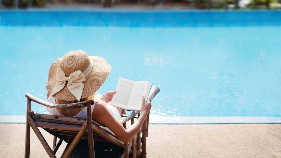 Woman sits by pool soaking up the sun.