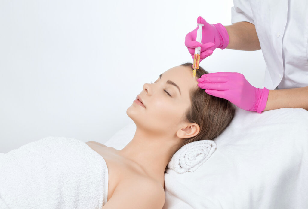 Pretty woman undergoes forehead injection of neuromodulators.